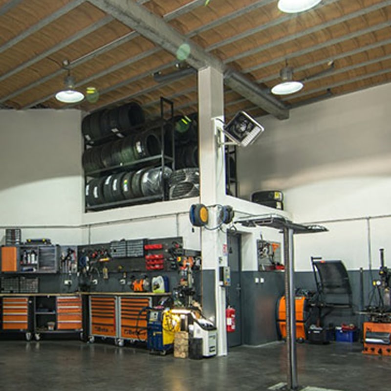 Atelier mécanique professionnel: Pneus & Équipement Atelier mécanique propre et organisé avec étagères de pneus, armoires à outils Beta orange et gris, et équipements de garage spécialisés.