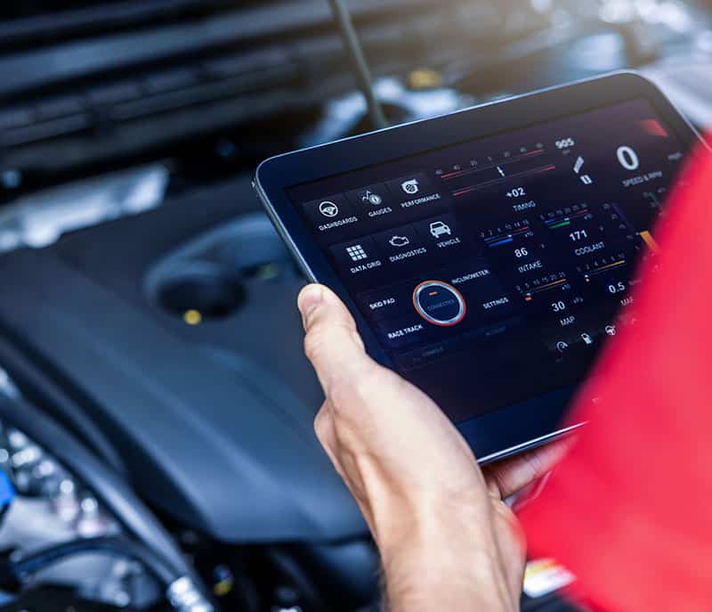 Main tenant une tablette affichant un diagnostic automobile CONNECTED. L'écran montre des données moteur, vitesse, RPM, température.