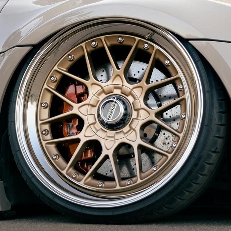 Sublime Jante BBS Dorée Poli - Look Voiture Abaissée Jante BBS or/bronze multi-rayons, bord poli, étrier rouge, sur voiture abaissée. Disque de frein percé. Texte "BBS".