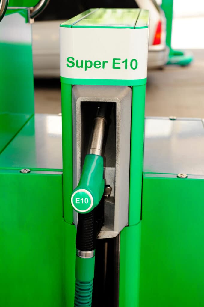Carburant E10 : essence Super E10 à la pompe verte. Pompe à carburant verte et blanche affichant "Super E10" avec le pistolet vert marqué "E10". Prête à distribuer de l'essence.